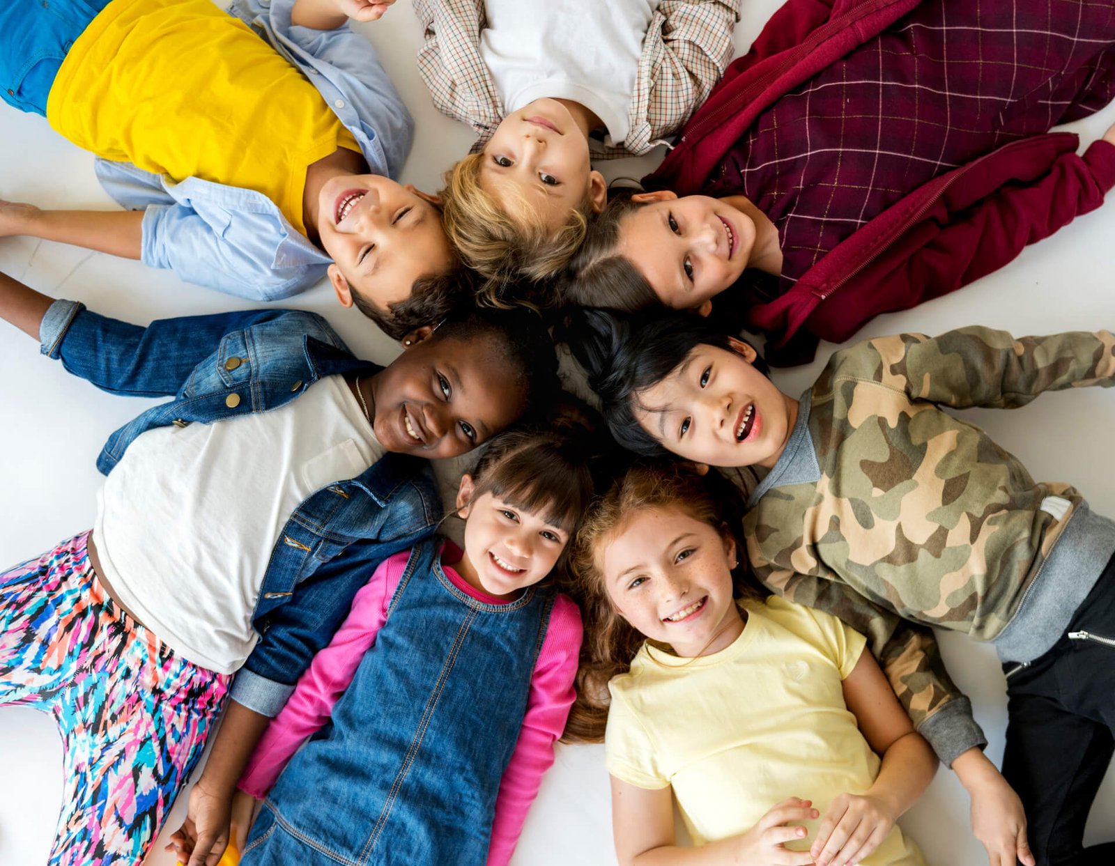 Niños tumbados en círculo sonriendo juntos