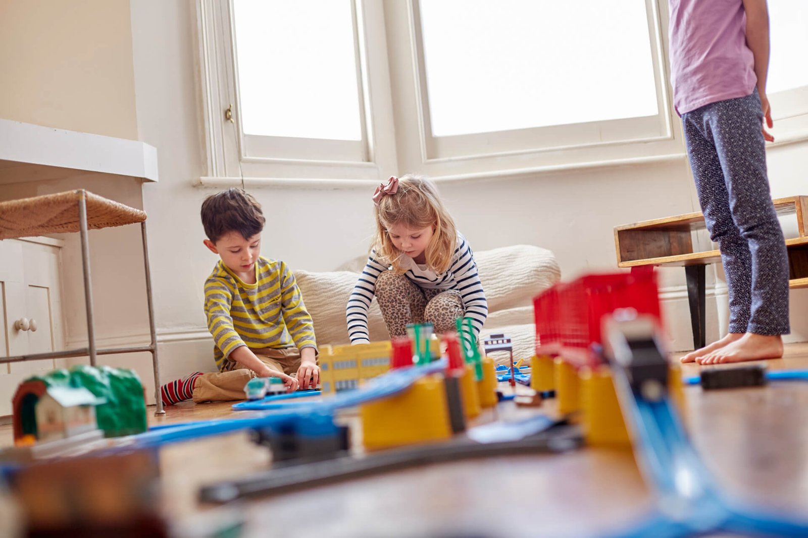 Niños jugando con trenes de madera en una sala luminosa